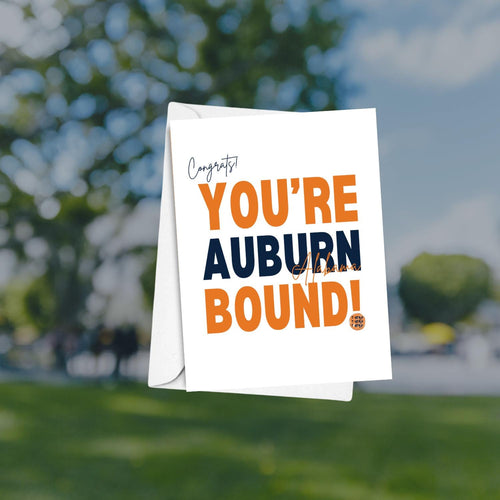 Card with 'Congrats! You're Auburn Bound!' text against a blurred outdoor background